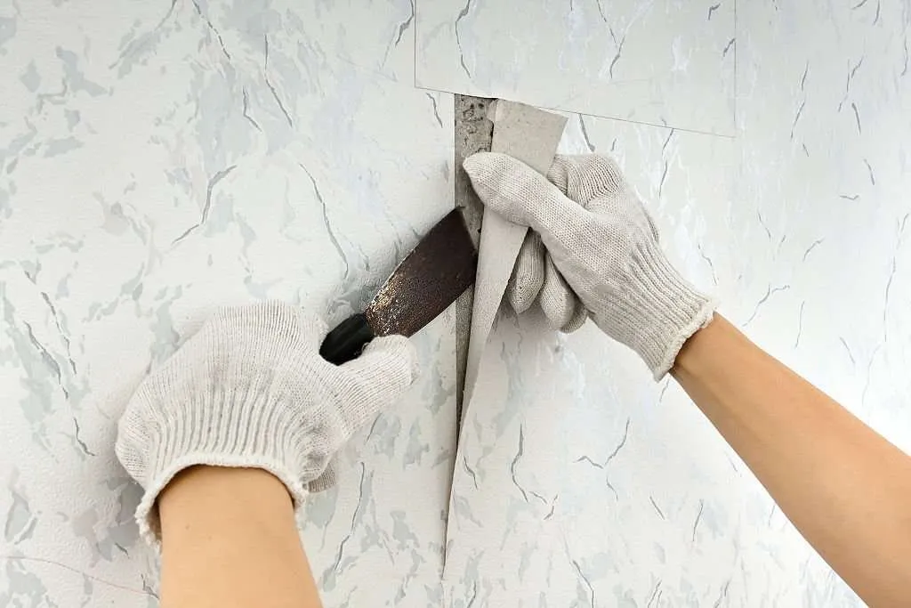 a man removing wall stickers using a blade