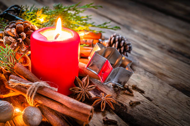 red Candle with Cinnamon Sticks on a wood table