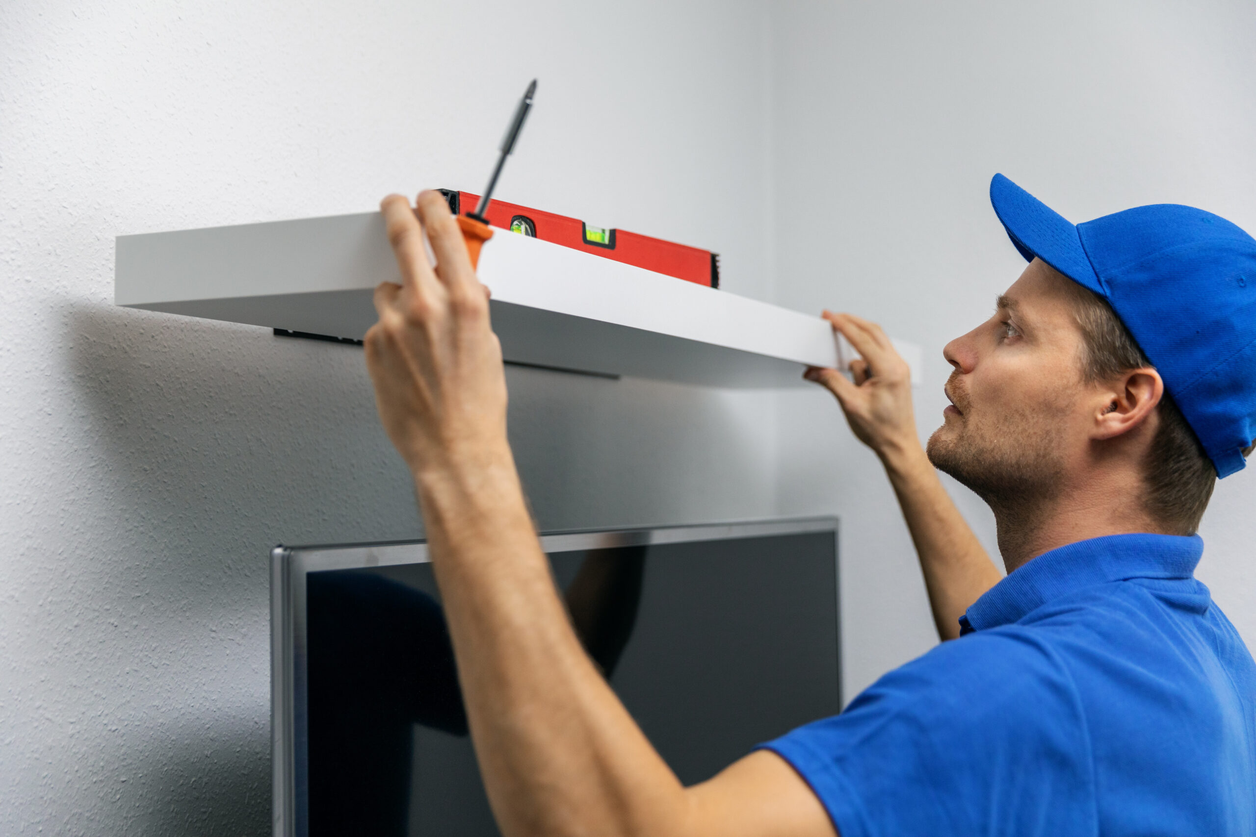 A man installing wall shelves