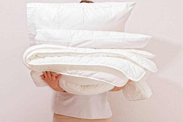 a man holding sheets and pillows